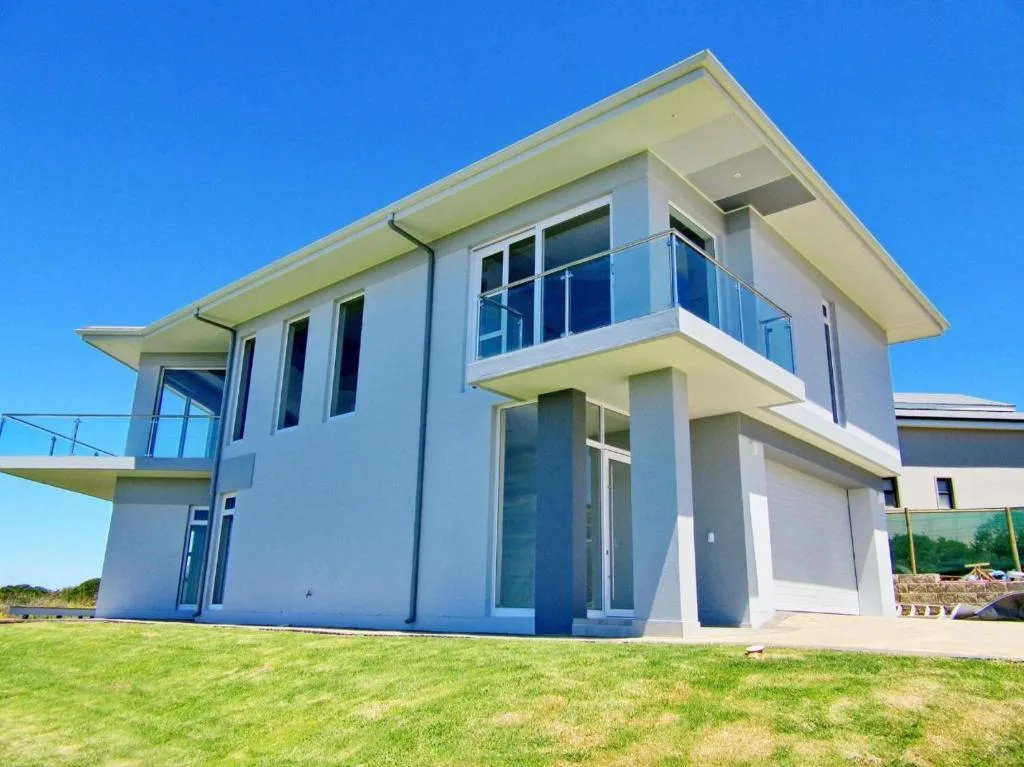 Modern white villa with glass balconies and manicured green lawn