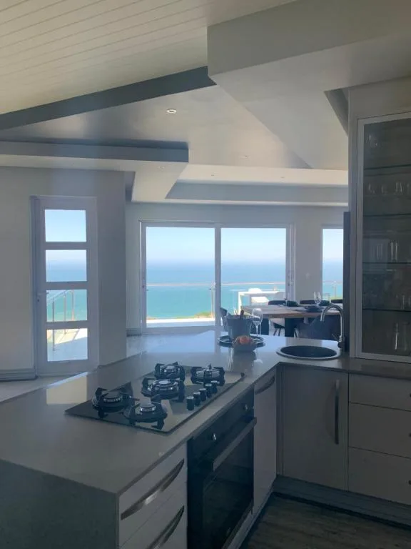 Modern kitchen with gas cooktop overlooking ocean views through large windows