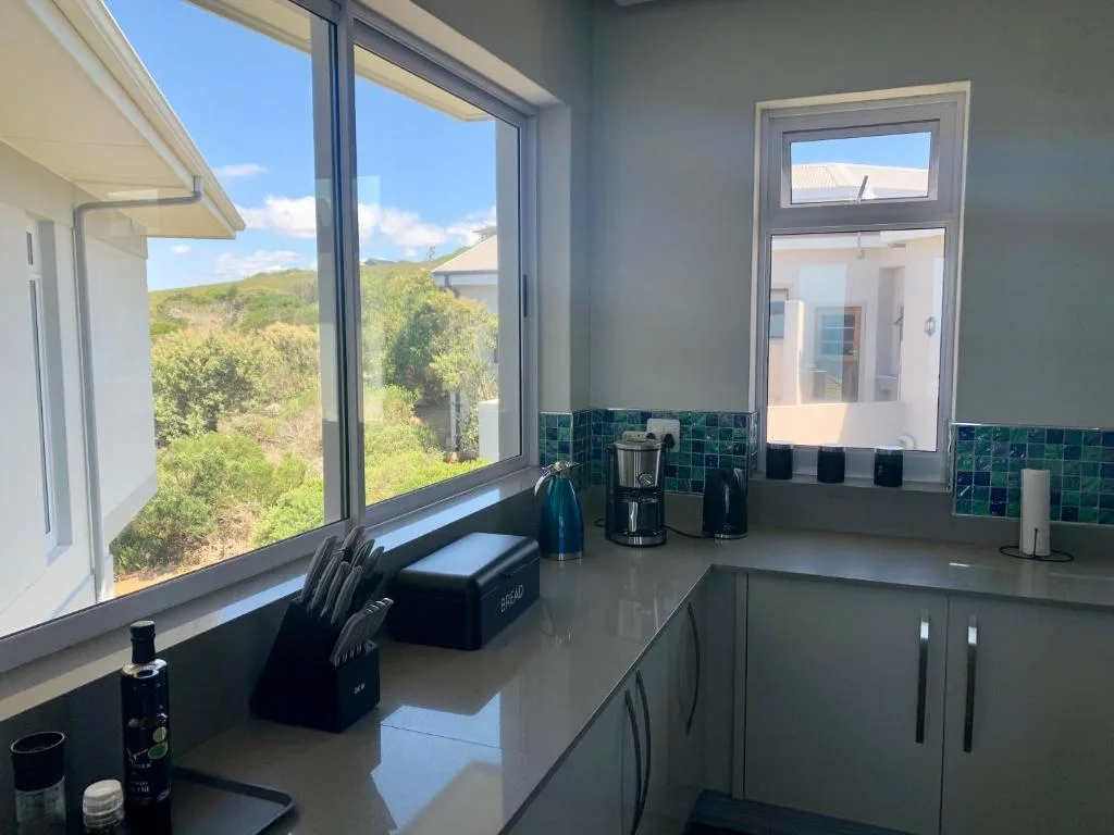 Modern kitchen with green tile backsplash and scenic mountain views through windows
