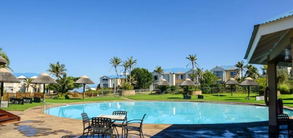 Large swimming pool with lounge chairs and resort buildings in background