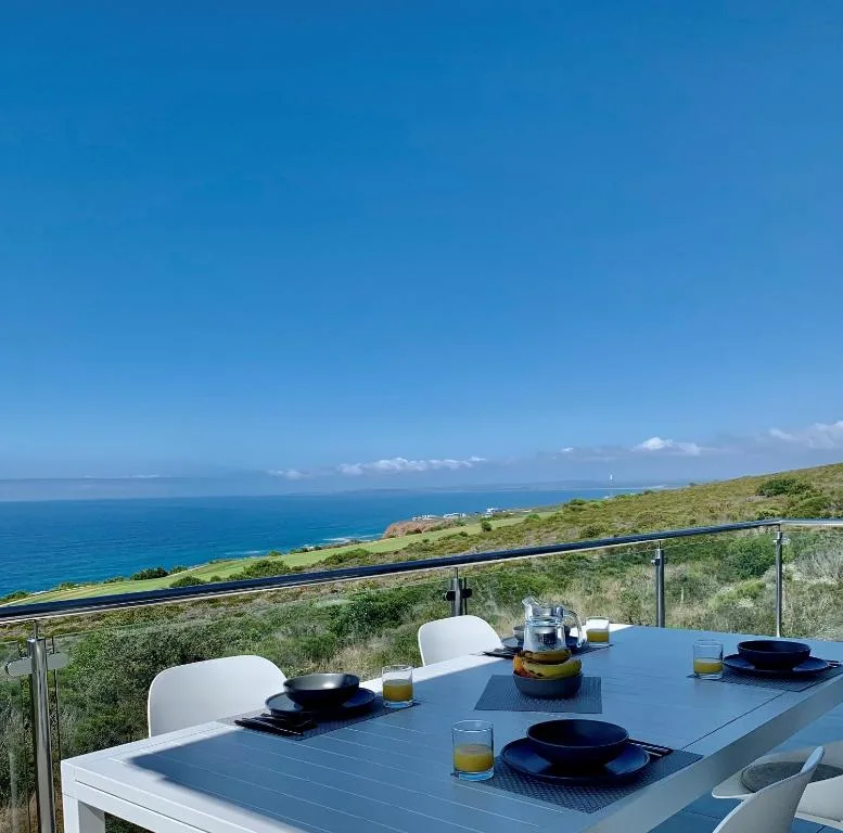 Ocean and coastline vista from elevated deck with dining table