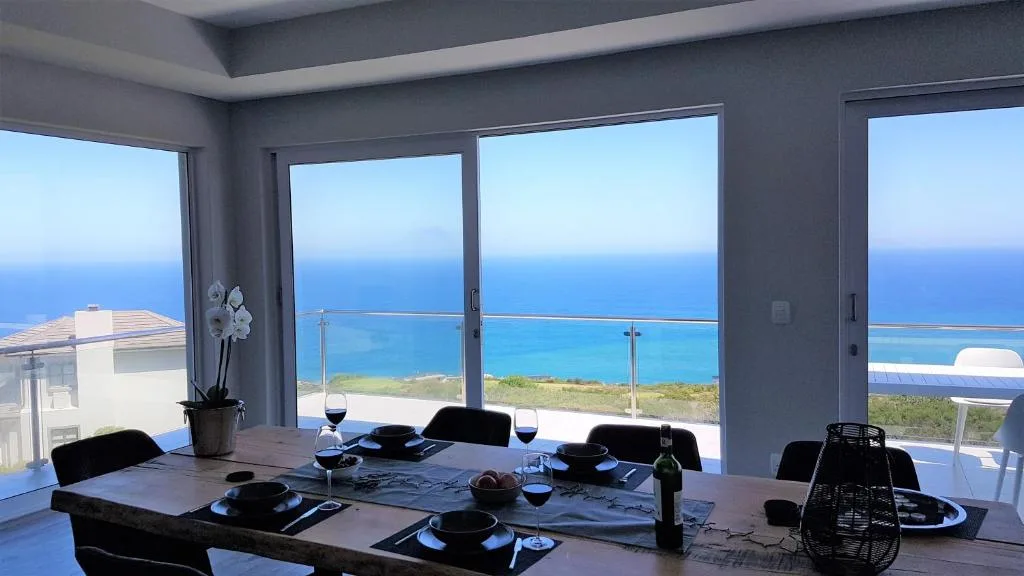 Expansive ocean and coastline view through large windows from dining area