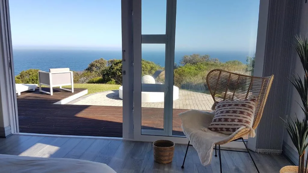 Ocean vista through open glass doors, coastal vegetation and blue horizon beyond