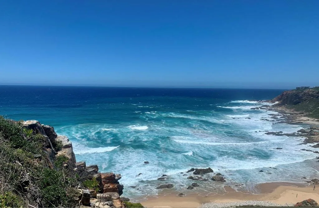 Turquoise ocean waves and rocky coastline under clear blue sky