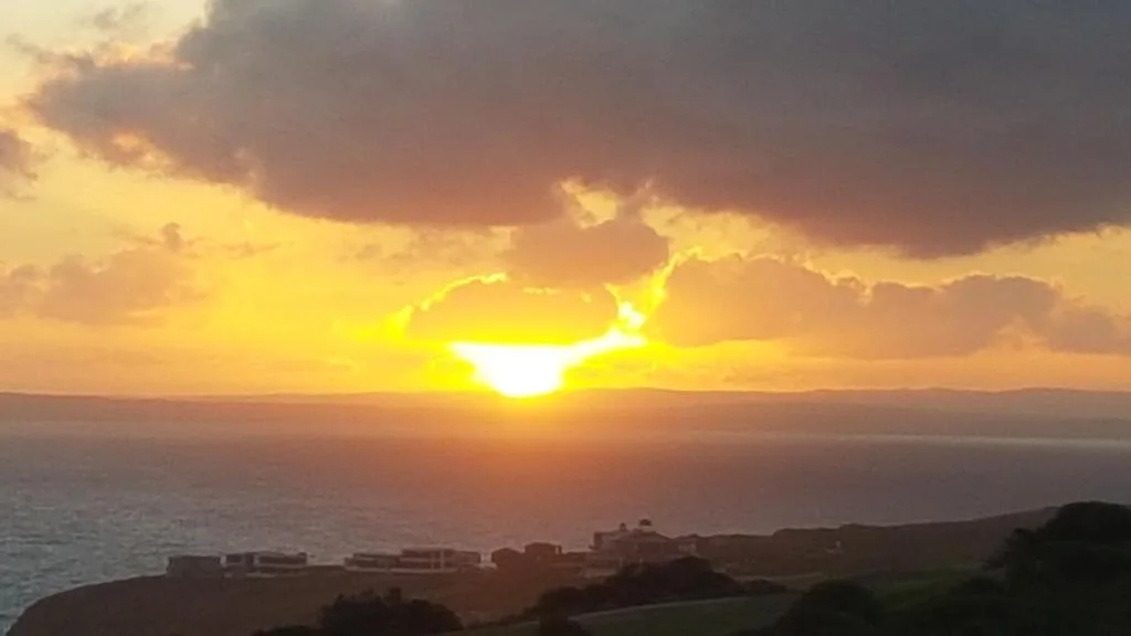 Golden sunset over ocean with dramatic cloudy sky and coastline
