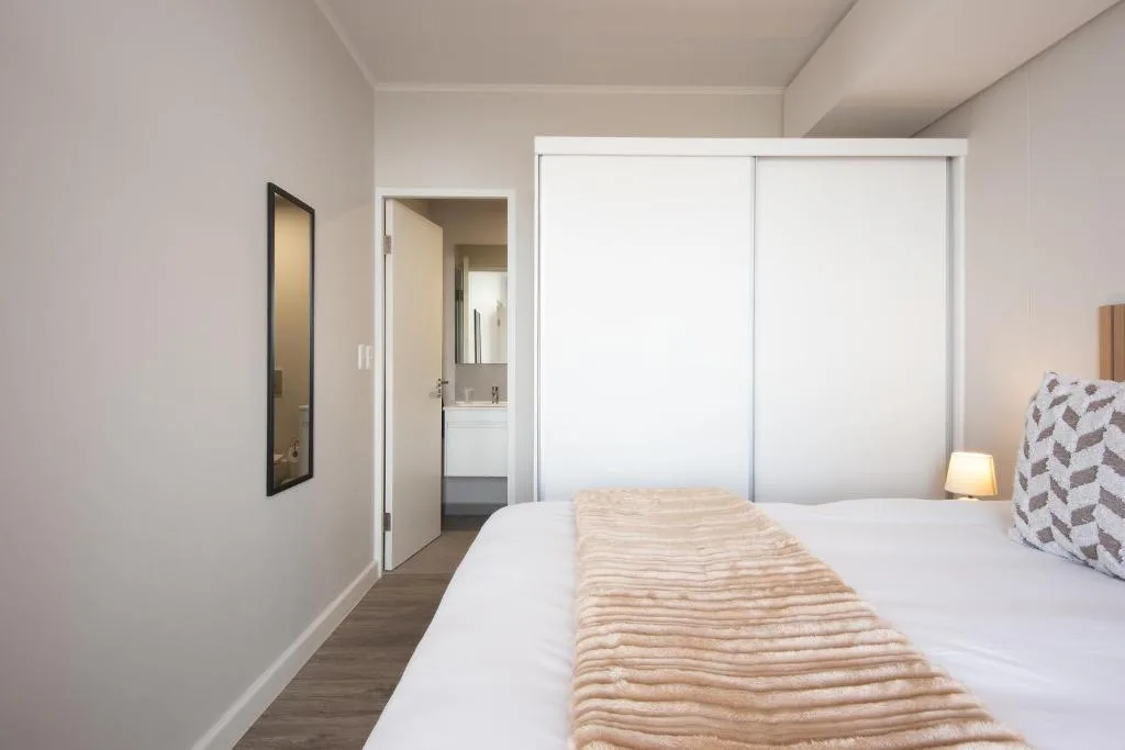 Modern bedroom with double bed and en-suite bathroom access through sliding doors