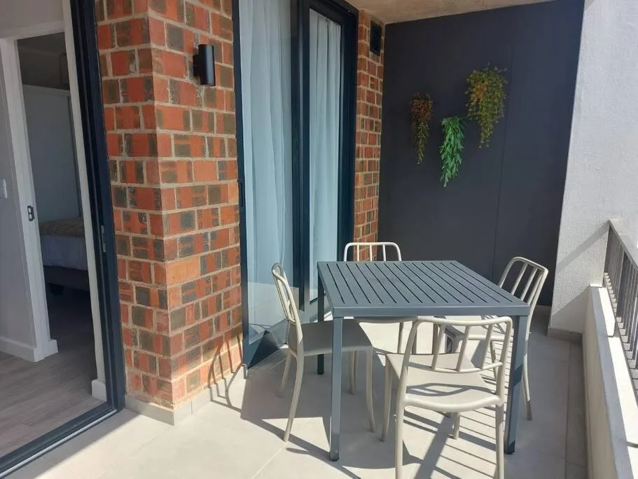 Outdoor patio with dining table and chairs, brick wall detail