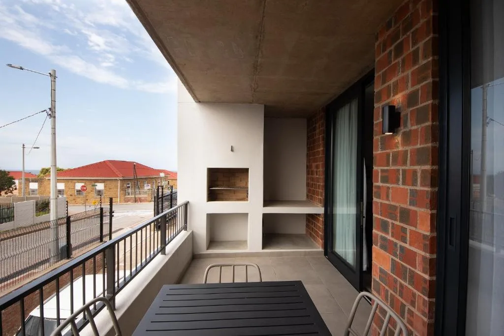Modern balcony with black railing, built-in shelving, and town views