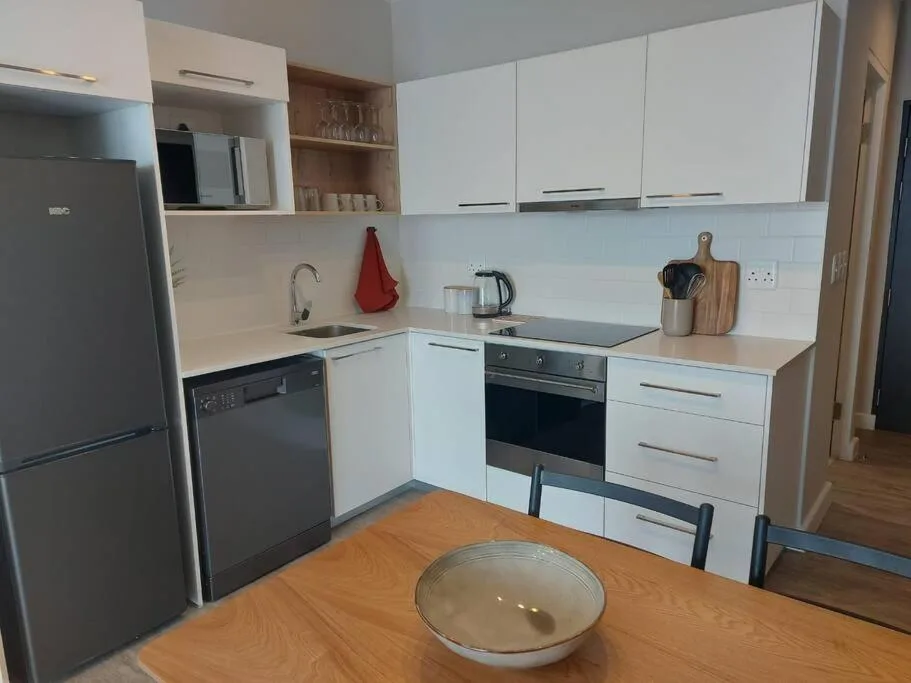 Modern kitchen with white cabinetry, stainless steel appliances, and wooden countertops