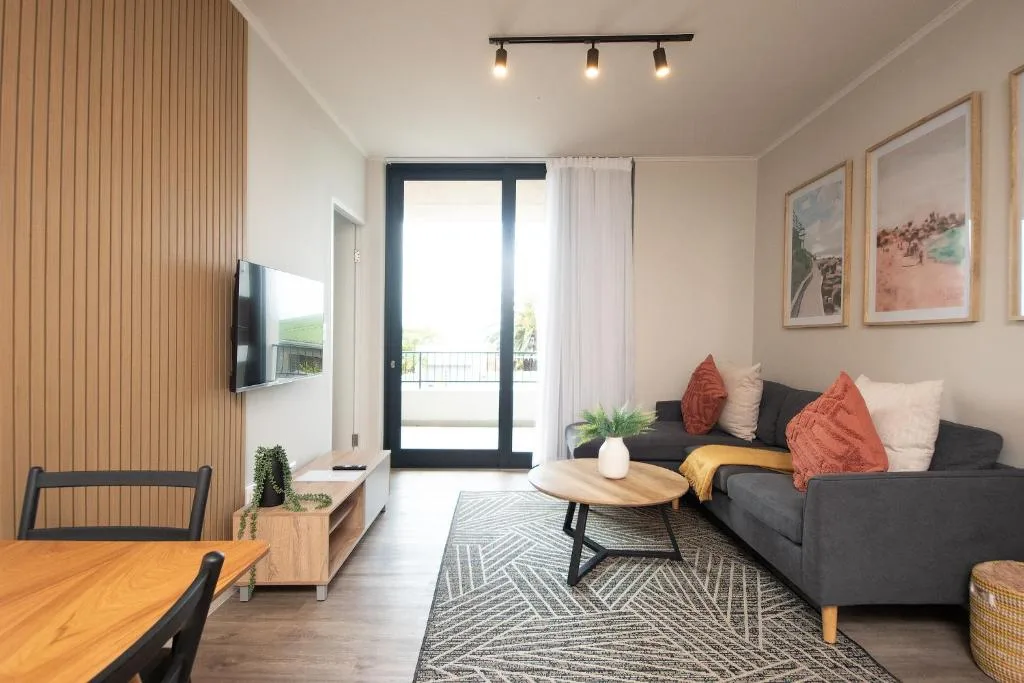 Modern lounge with dark sofa, wooden accents, and sliding doors to deck