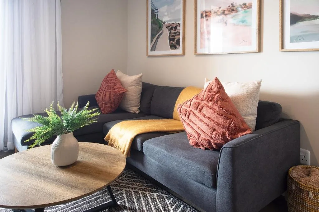 Contemporary lounge with dark sofa, colorful cushions, and scenic artwork