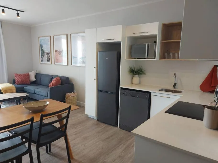 Open-plan lounge and kitchen with blue sofa, dining table, modern appliances