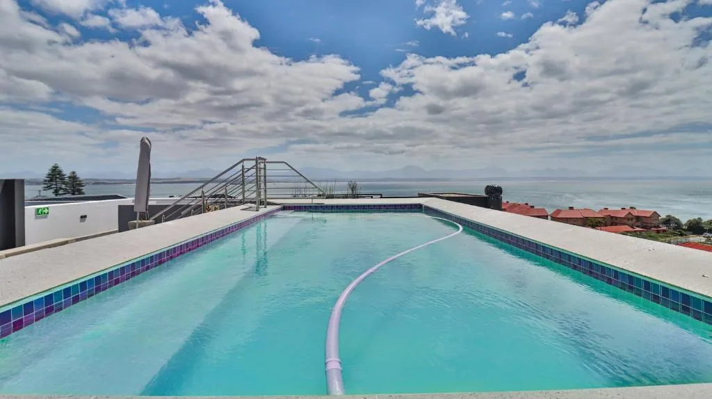 Sparkling turquoise swimming pool with ocean and mountains in background