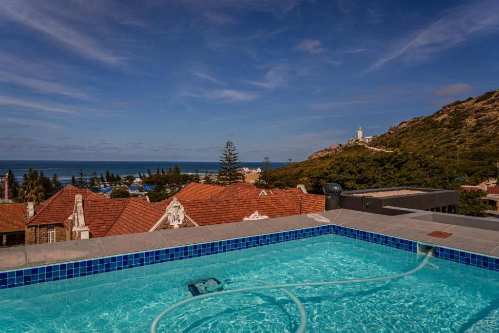 Crystal blue swimming pool overlooking Mossel Bay and distant lighthouse
