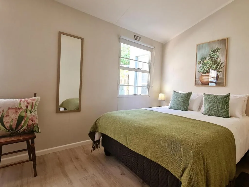 Bright bedroom with queen bed, green throw, and natural light from window