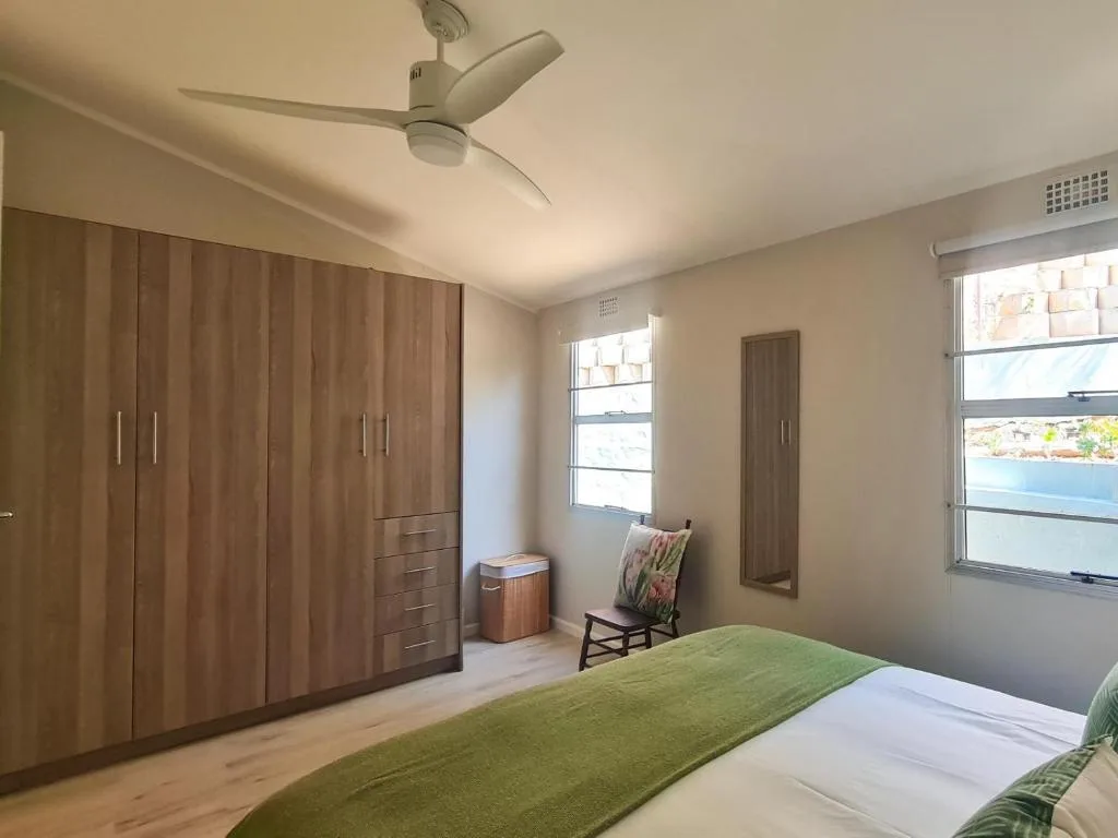 Spacious bedroom with sea view windows, wooden wardrobe, and green bedding