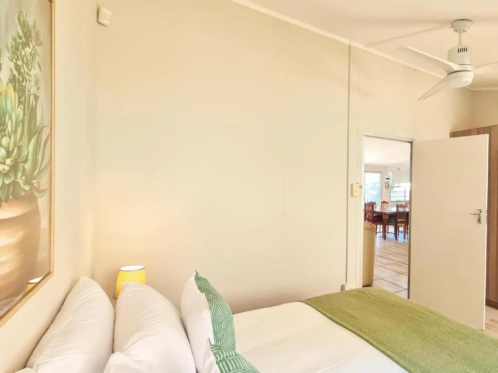 Bright bedroom with white pillows, green accents, ceiling fan