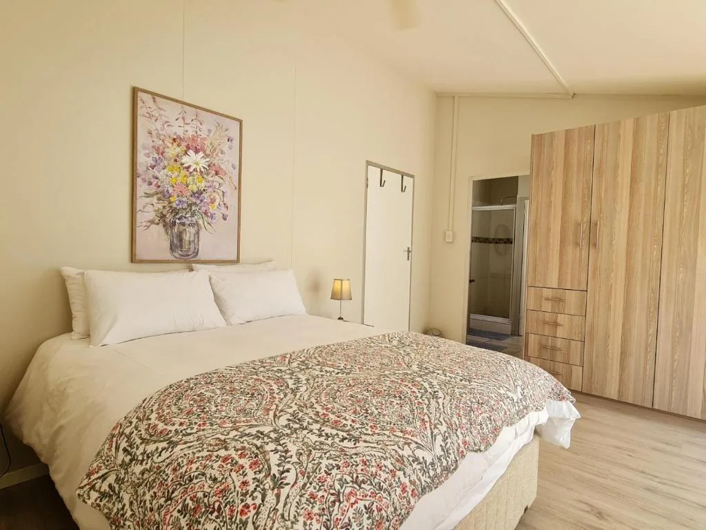 Spacious bedroom with queen bed, floral artwork, and wooden wardrobe