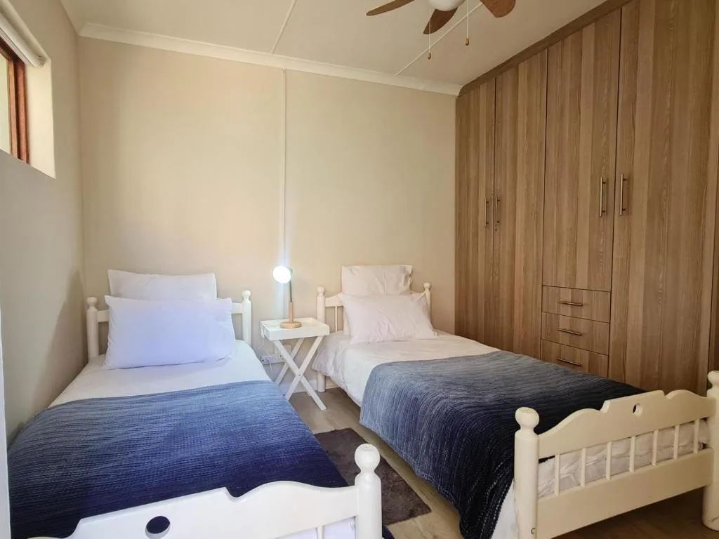 Twin bedroom with white beds, wooden wardrobe, and pendant lighting