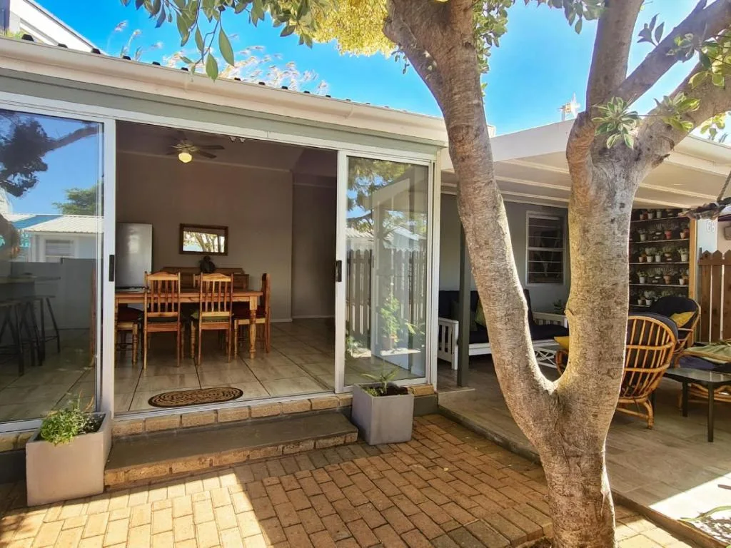Shaded outdoor patio with dining table and comfortable seating under mature trees