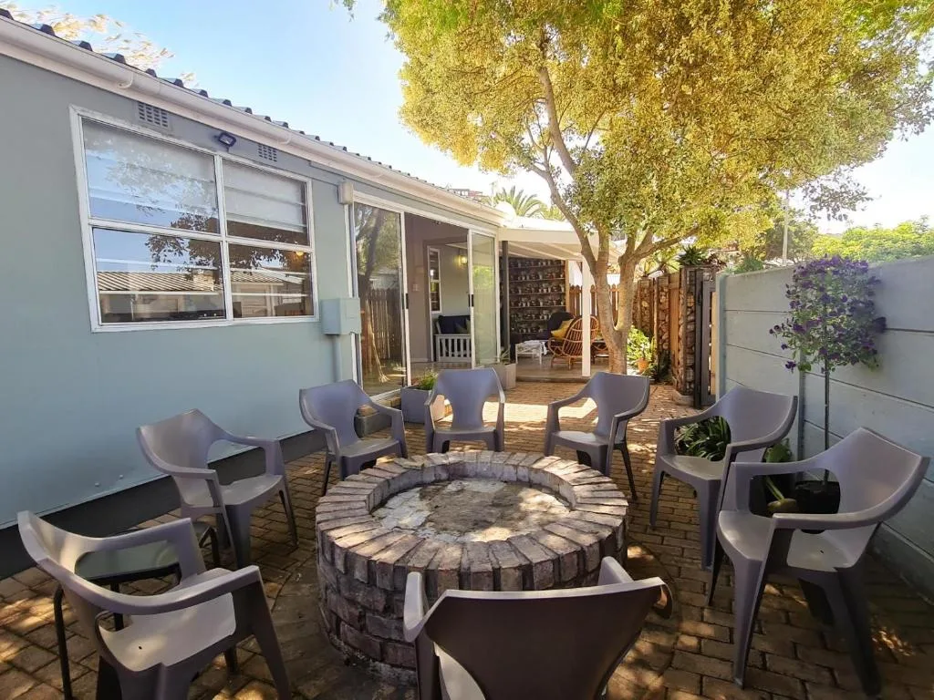 Outdoor patio with fire pit, modern chairs, and mature tree shade