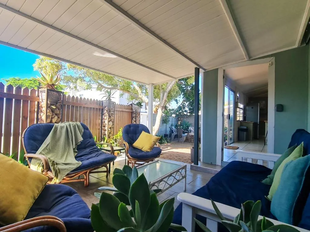 Covered patio with comfortable seating, retractable awning, and garden views