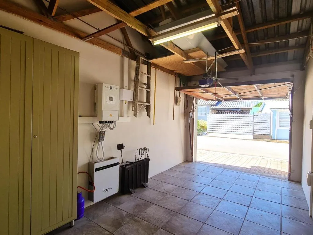 Garage interior with electrical panel, battery storage, and open doors