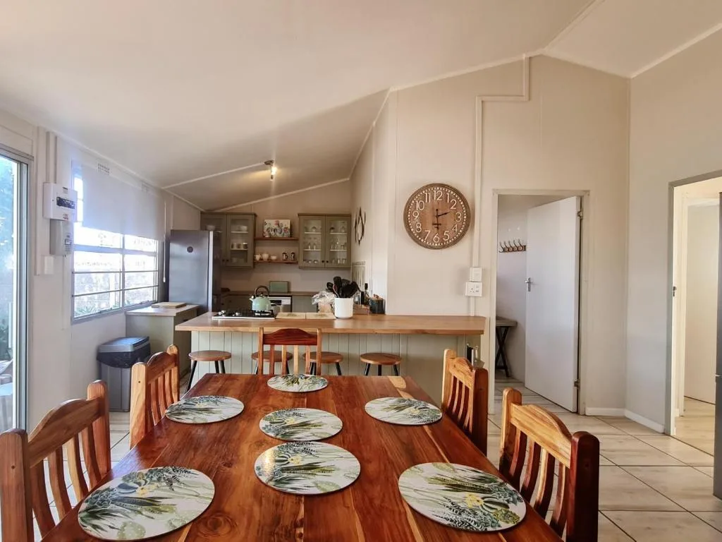 Dining table with wooden chairs and place settings in bright kitchen area
