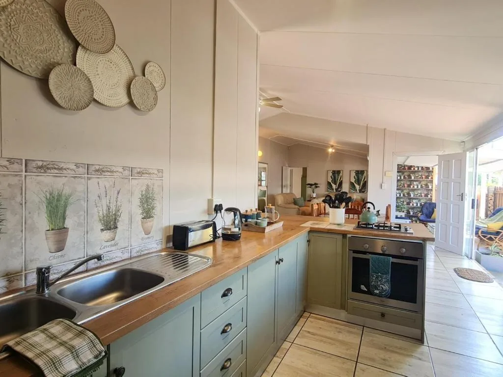 Modern kitchen with sage green cabinetry, wooden counters, and decorative wall plates