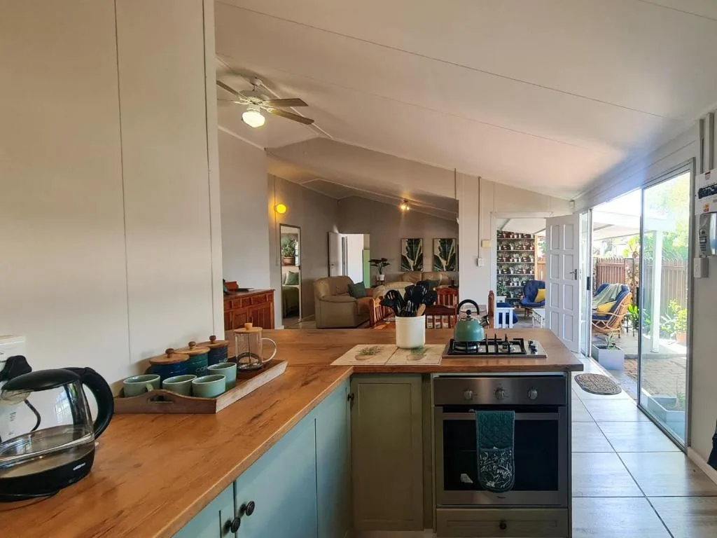Open-plan kitchen with wooden counters, green cabinetry, and stove overlooking lounge area