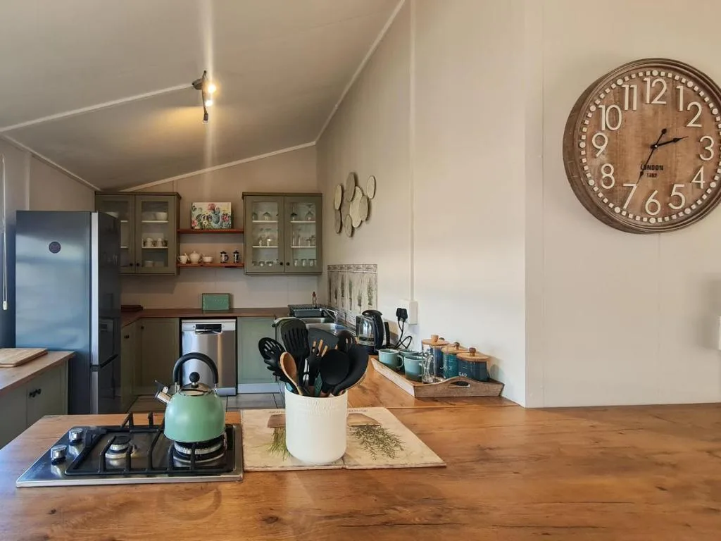 Modern kitchen with wooden countertop, green kettle, and stainless steel appliances
