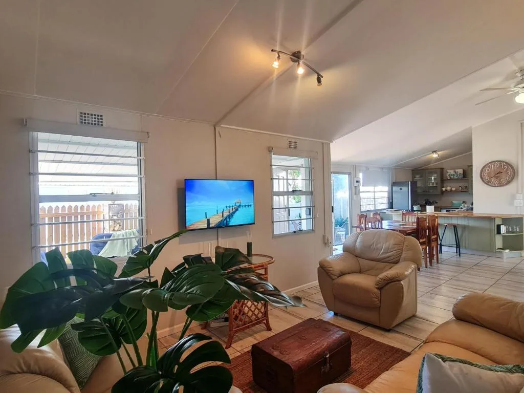 Bright living room with comfortable seating, wall-mounted TV, and ocean views