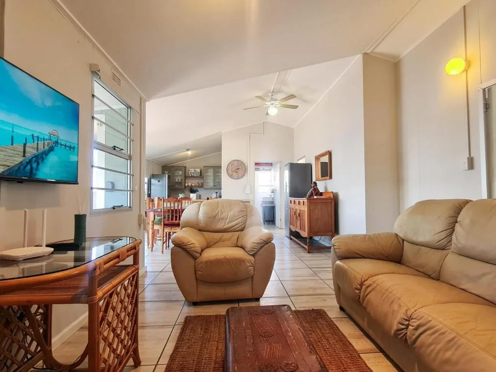 Open-plan lounge with tan leather seating and wall-mounted television