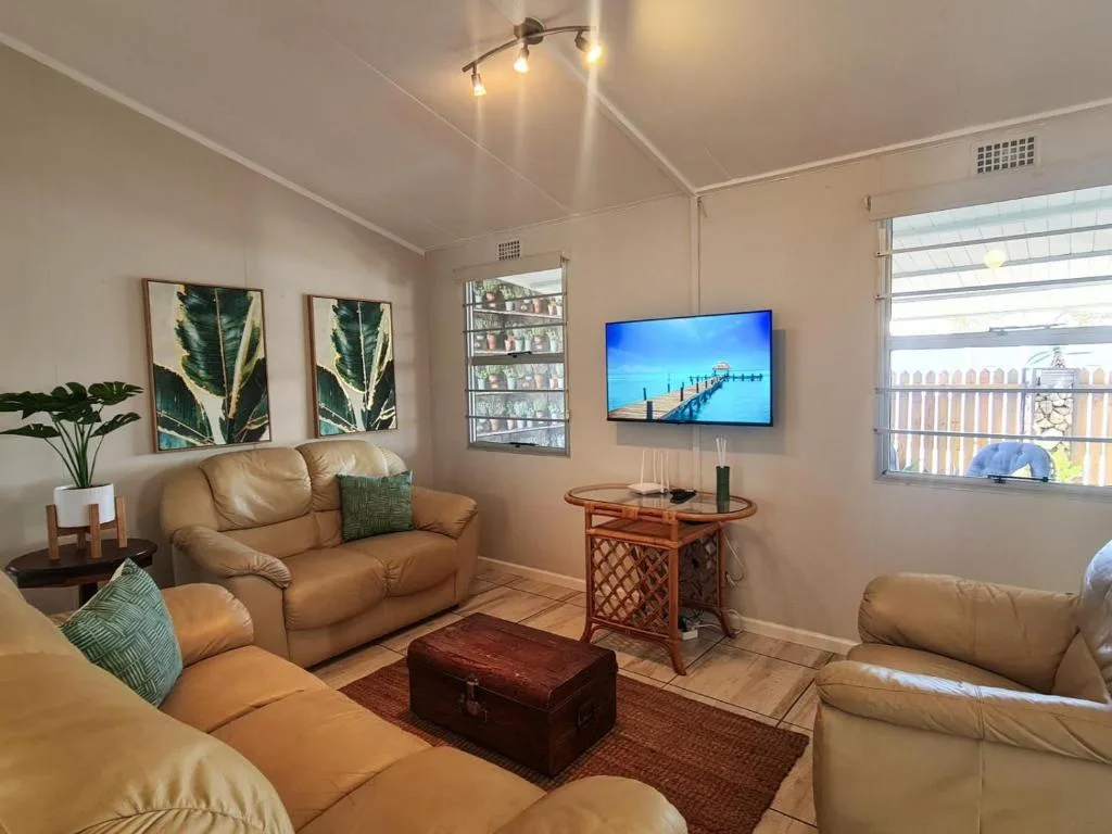 Spacious lounge with cream leather sofas, wall-mounted TV, and garden views