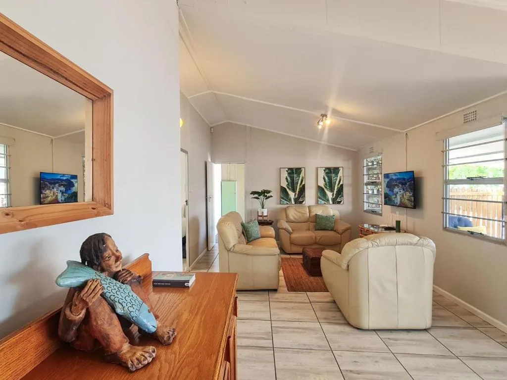 Spacious living room with cream sofas, coastal artwork, and wooden furniture