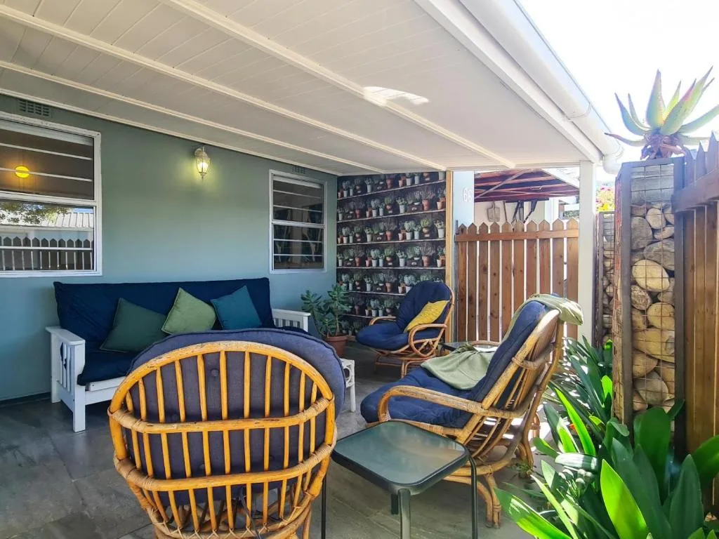 Covered lounge area with blue sofa, rattan chairs, and coastal decor