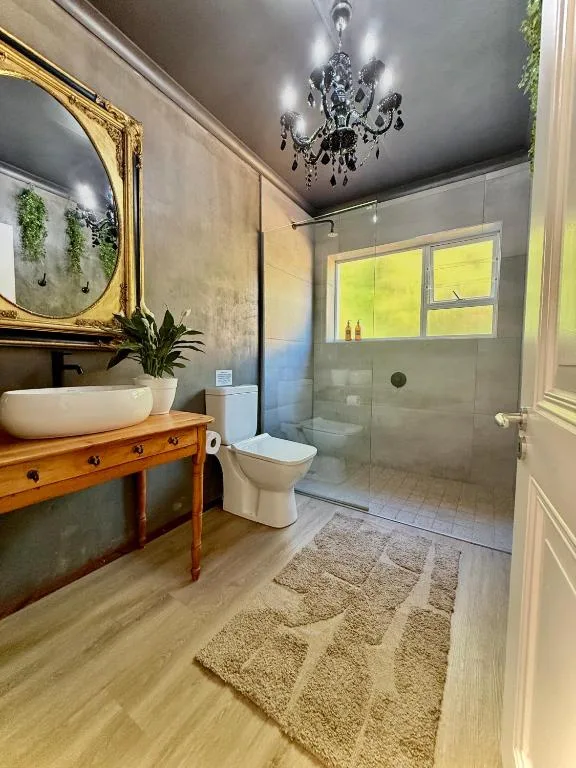 Modern bathroom with wooden vanity, round mirror, chandelier, walk-in shower