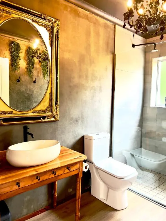 Modern bathroom with decorative mirror, wooden vanity, and shower area
