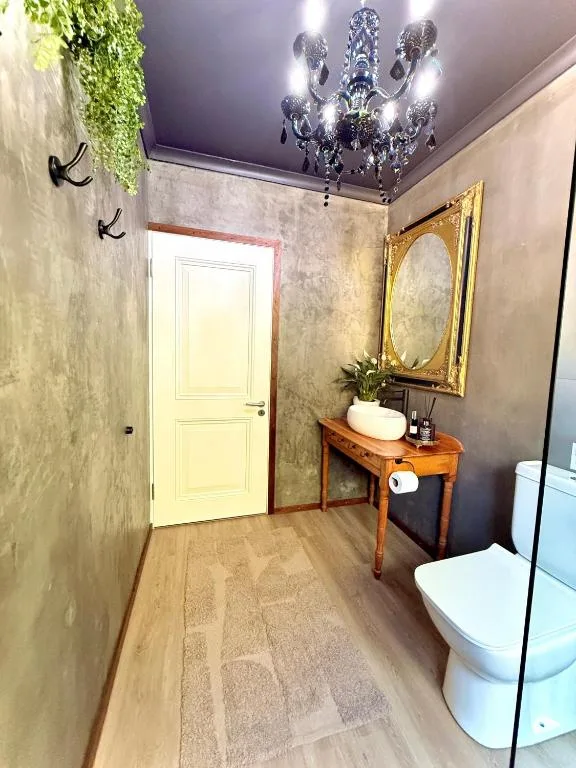 Modern bathroom with elegant chandelier, vanity mirror, and contemporary fixtures