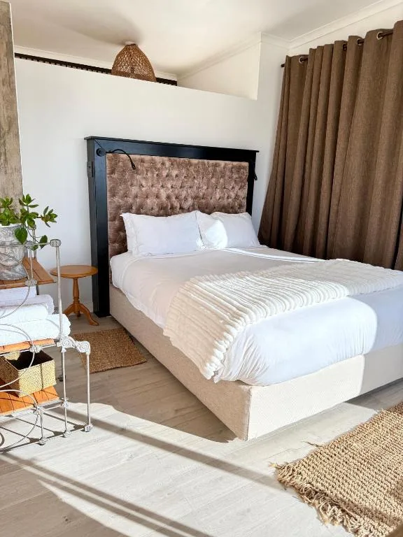 Bright bedroom with queen bed, upholstered headboard, and brown curtains