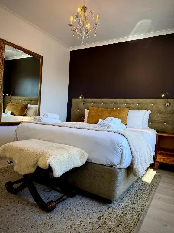 Modern bedroom with two beds, green headboards, and elegant chandelier