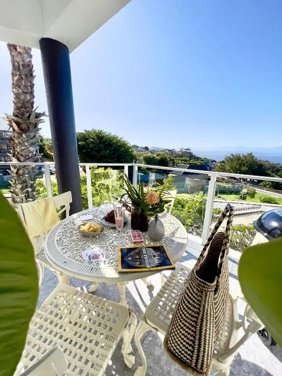 Outdoor balcony with dining table overlooking coastal landscape and gardens