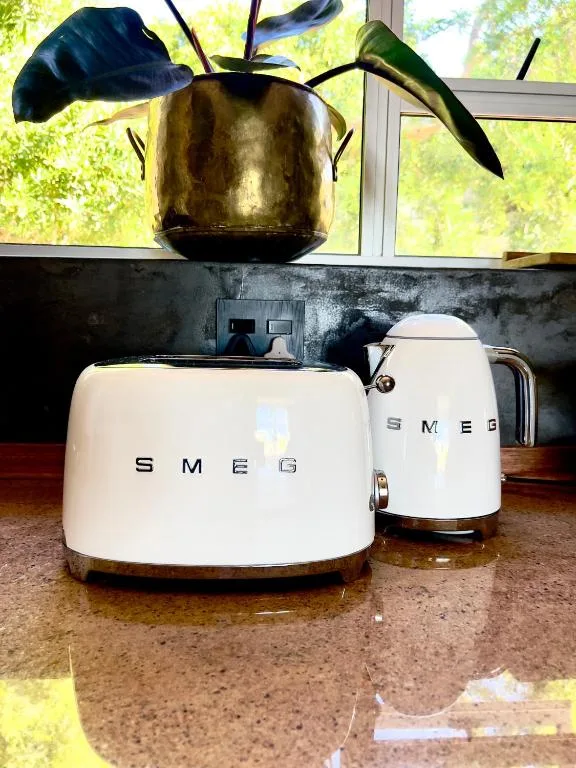 Stylish white SMEG toaster and kettle on kitchen counter with plant