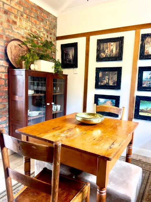 Wooden dining table with chairs in bright room with exposed brick