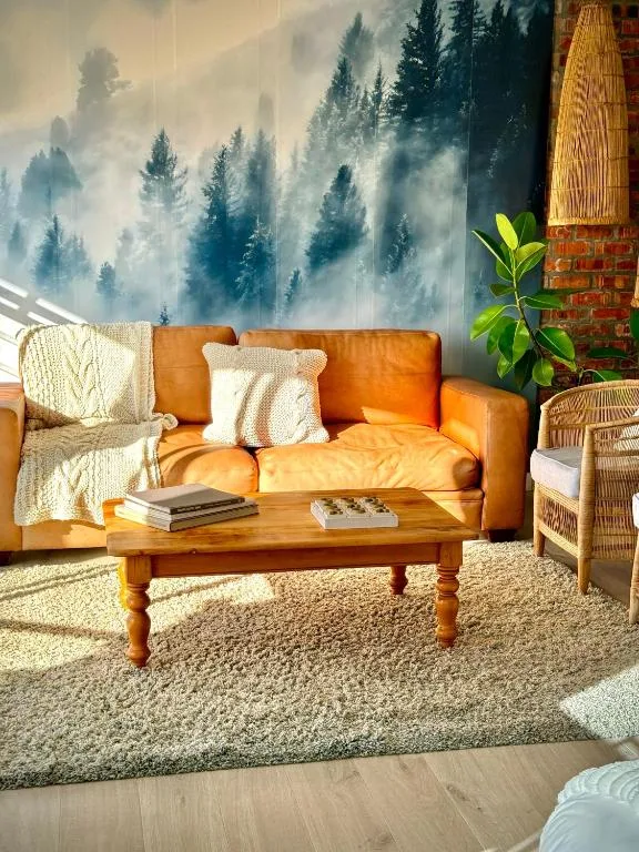 Warm orange leather sofa with forest mural and wooden coffee table