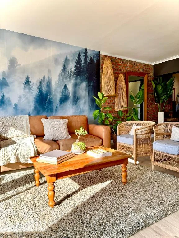 Modern lounge with cognac leather sofa, wooden coffee table, and forest mural wallpaper
