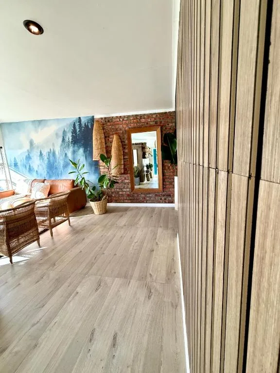 Modern lounge area with wicker furniture and forest landscape artwork