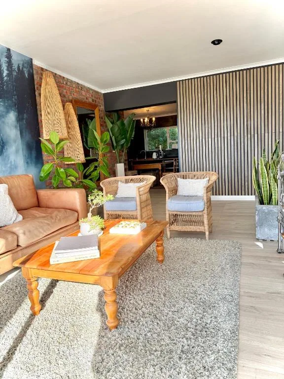 Modern living room with leather sofa, wicker chairs, wooden coffee table, and plants