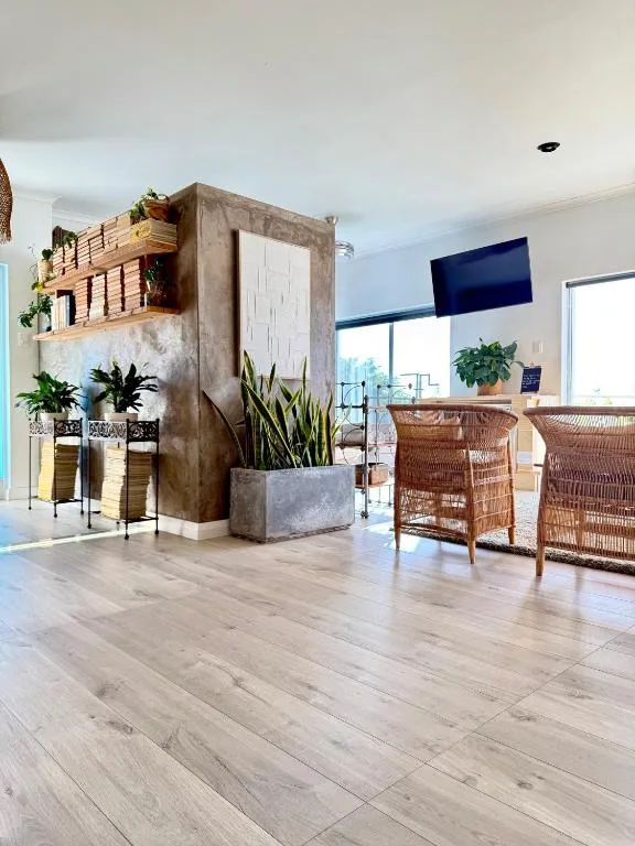 Modern lounge with wicker chairs, concrete feature wall, plants, and ocean views