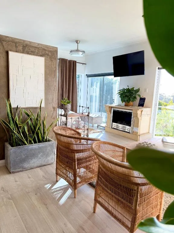 Bright living room with rattan chairs, fireplace, and garden views